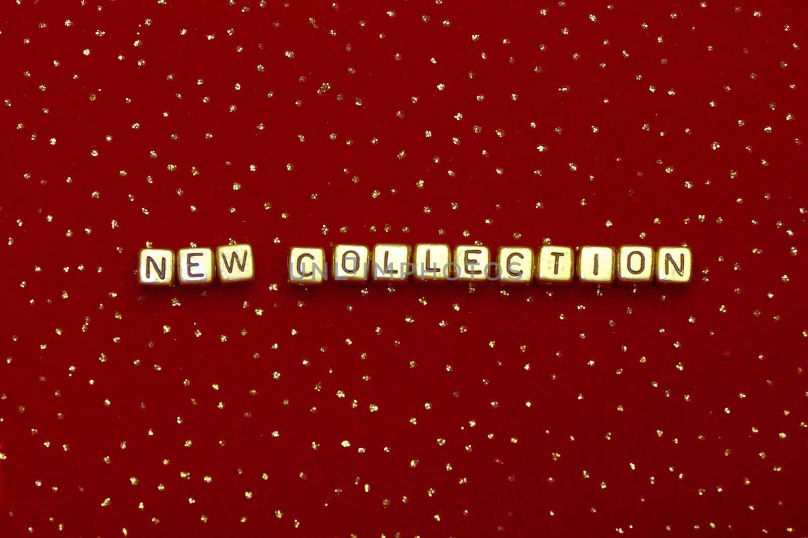 photo of words "new collection" of beads on a red velvet with sequins