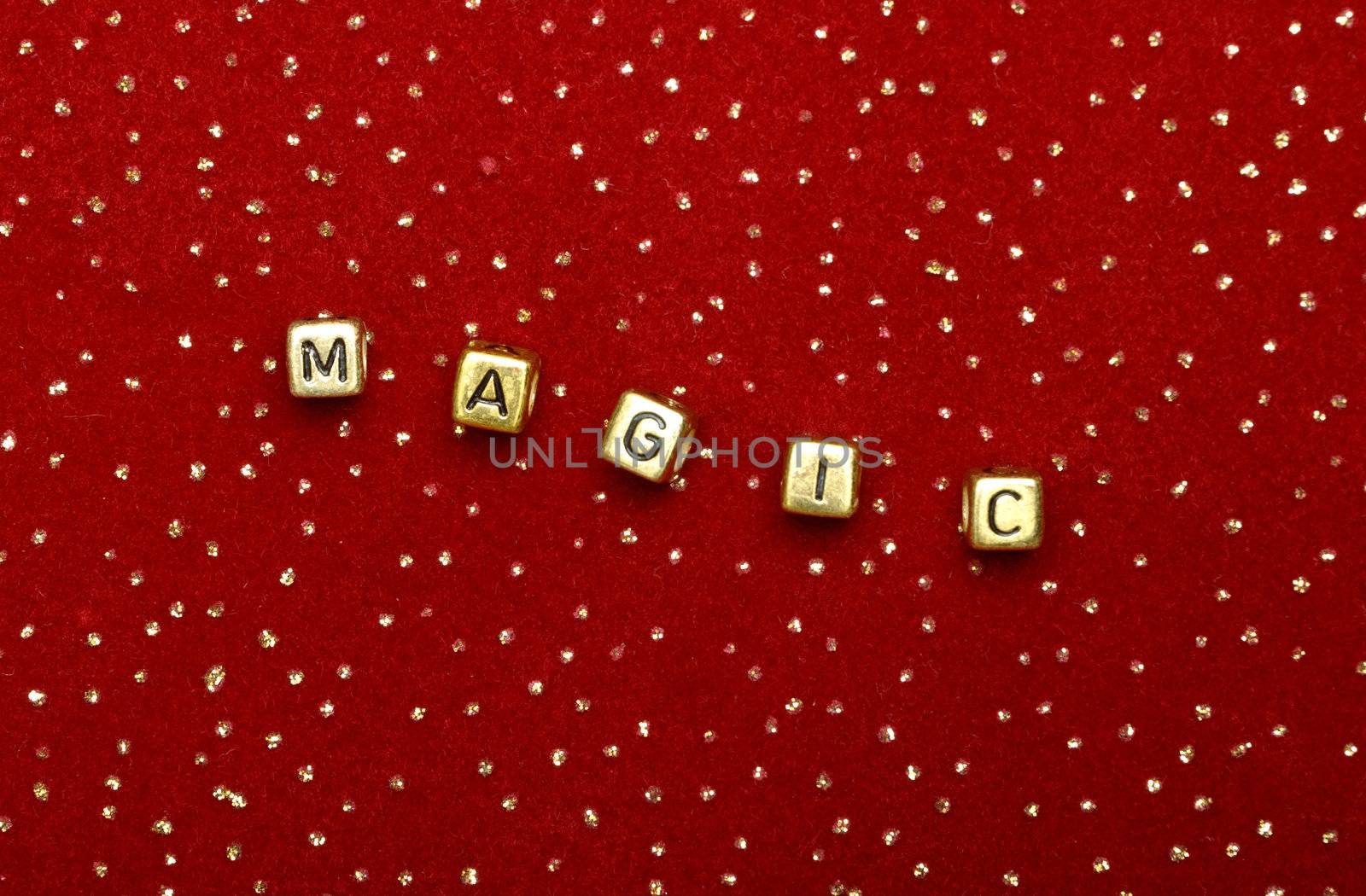 photo of word "magic" of beads on a red velvet with sequins