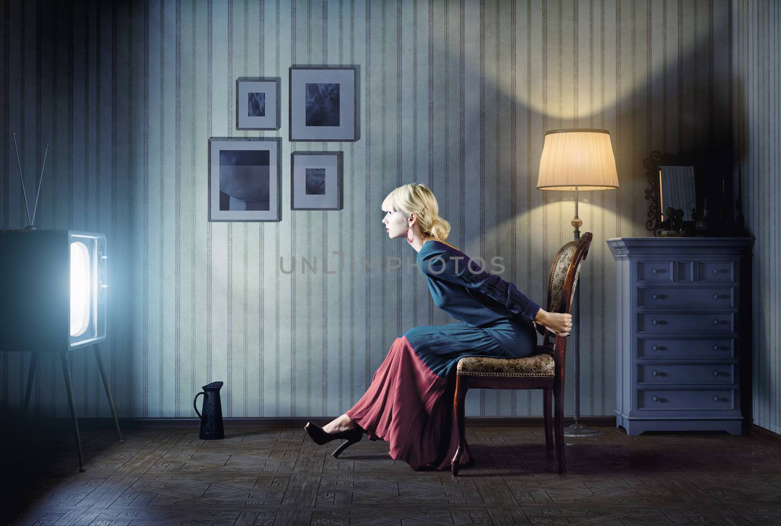 Young  woman sitting on a chair in vintage interior  and watching retro tv. She is very astonished while watching tv in dark room 