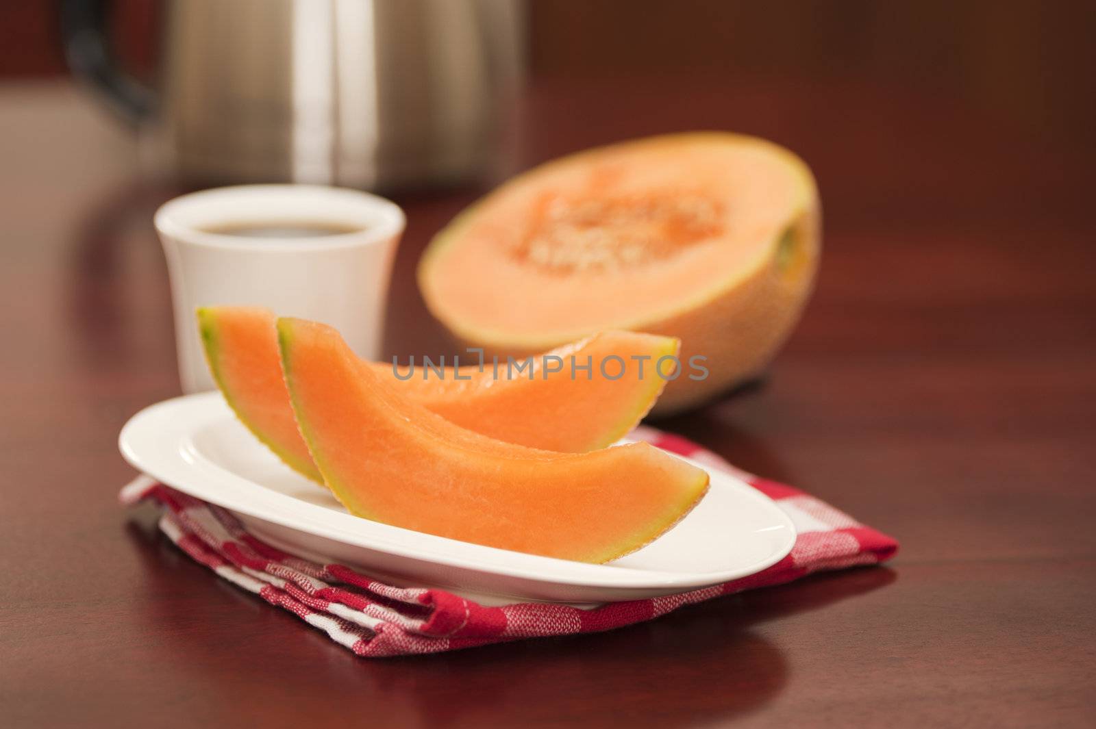 Wedges of fresh cantaloupe served with coffee.