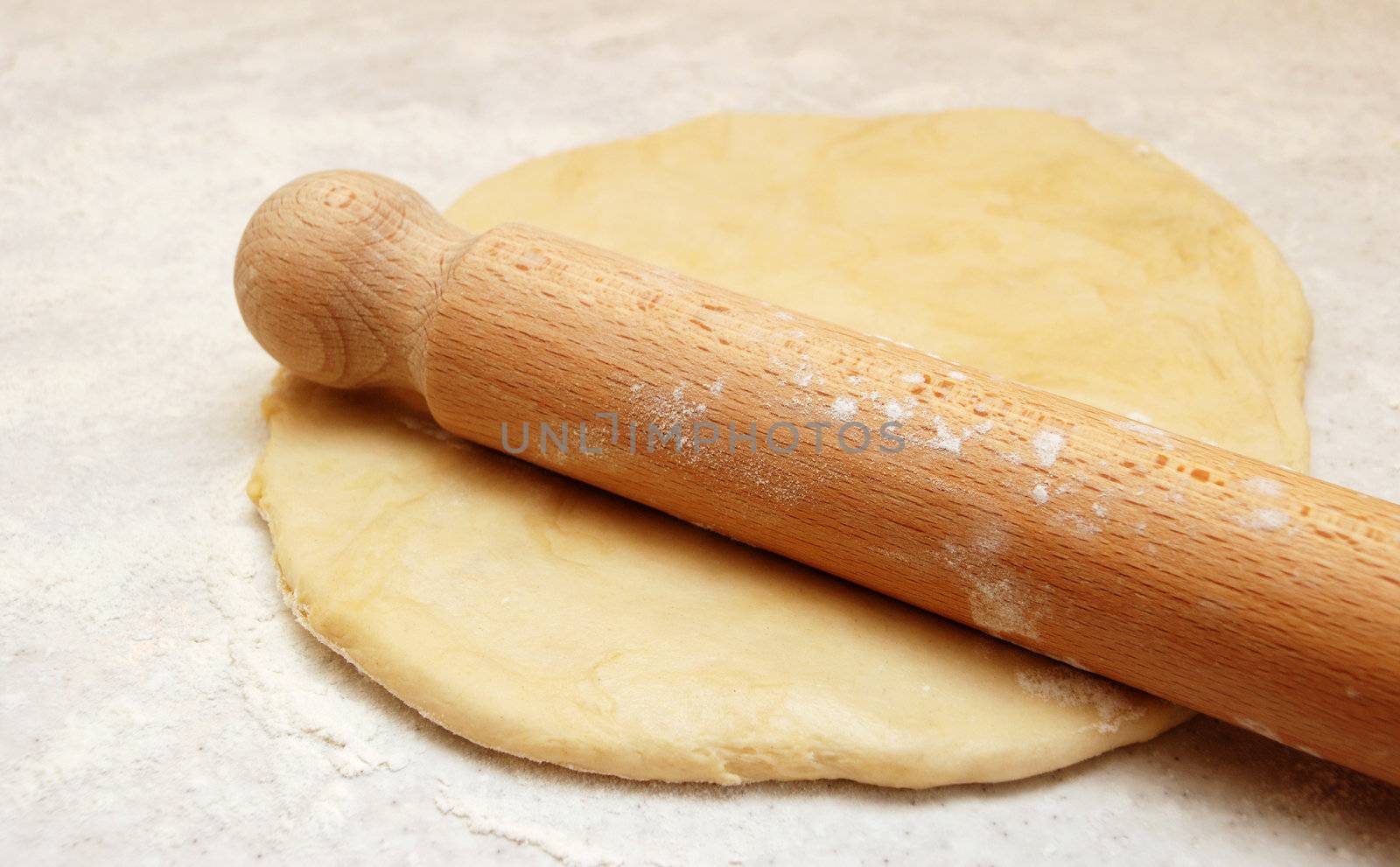 Wooden rolling pin, ready to roll out fresh pastry on a floured surface