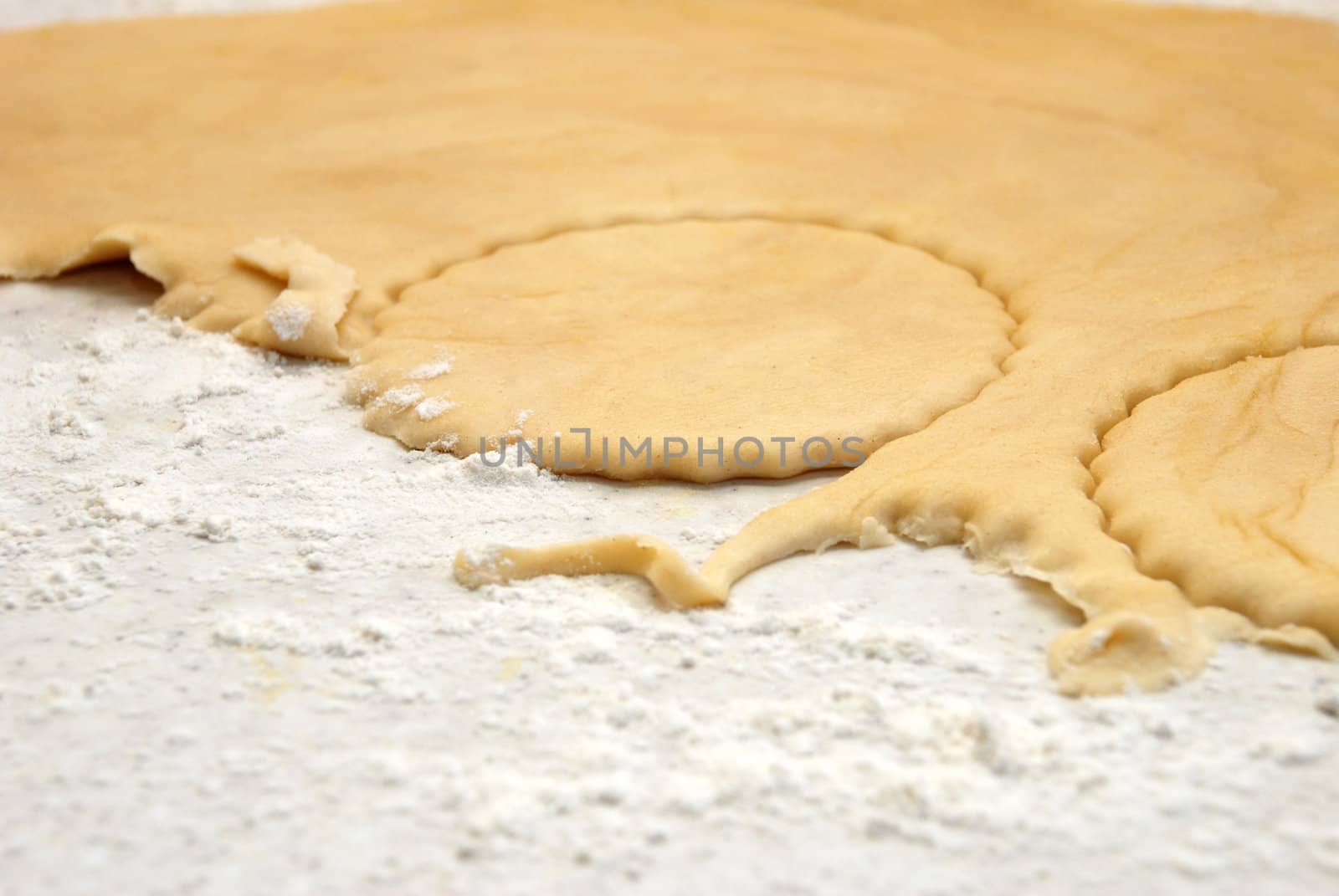 Detail of circles being cut from a sheet of fresh pastry with some shapes having already been removed