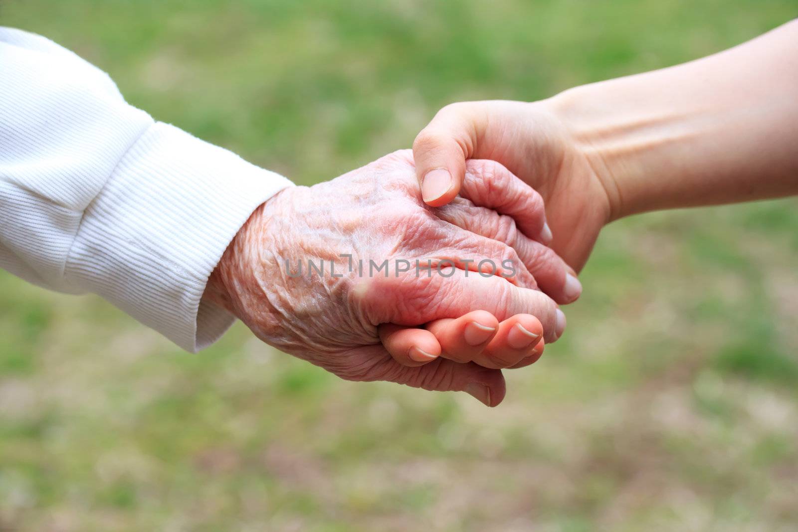 Senior lady and young women holding hands 