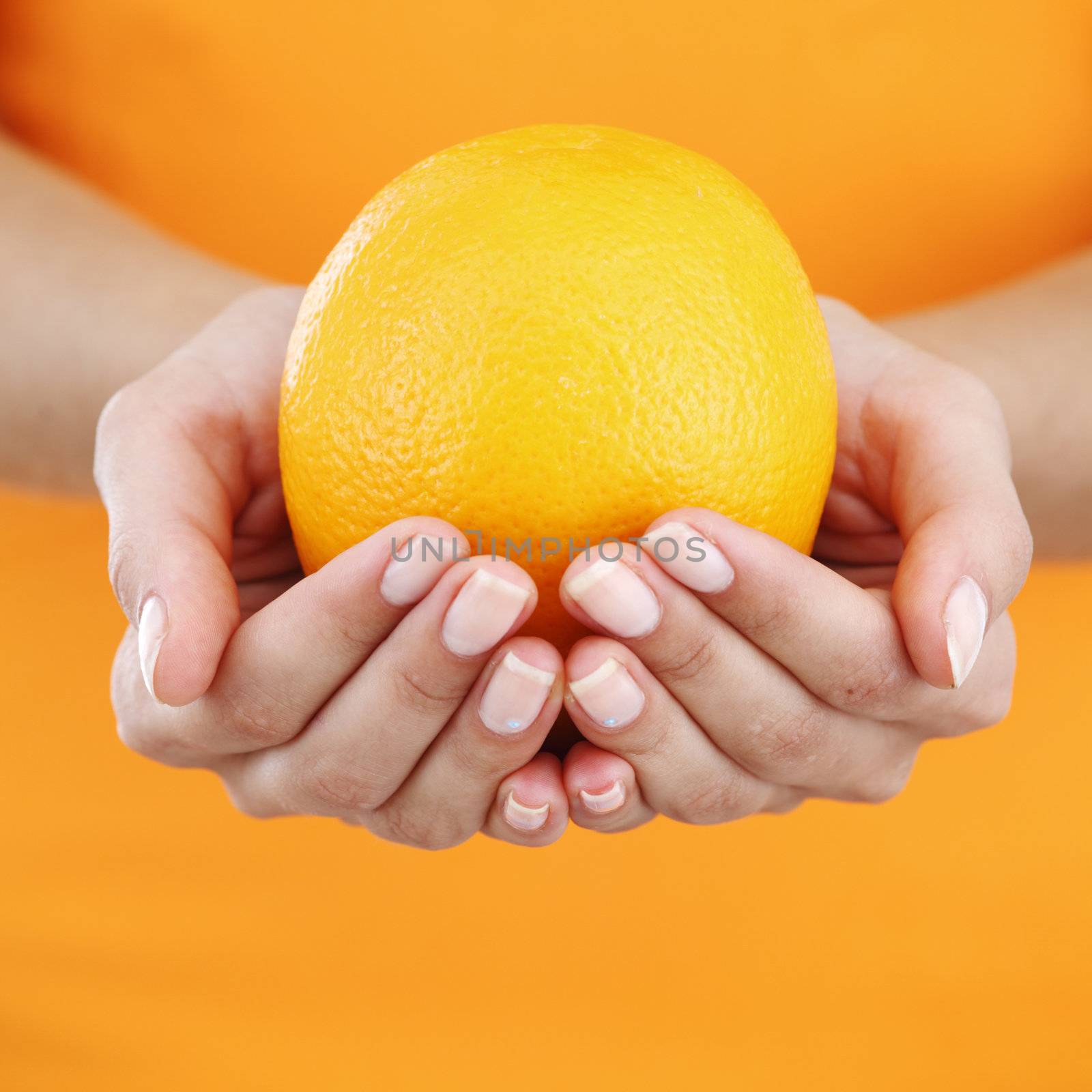 orange in woman hands close up