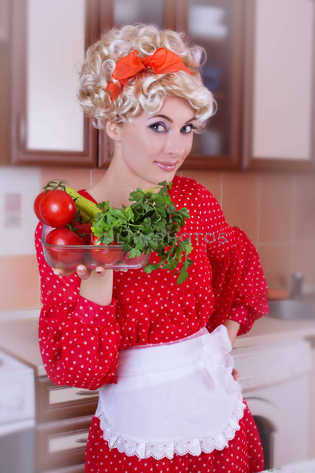 Pinup woman in red with fresh vegetables on kitchen