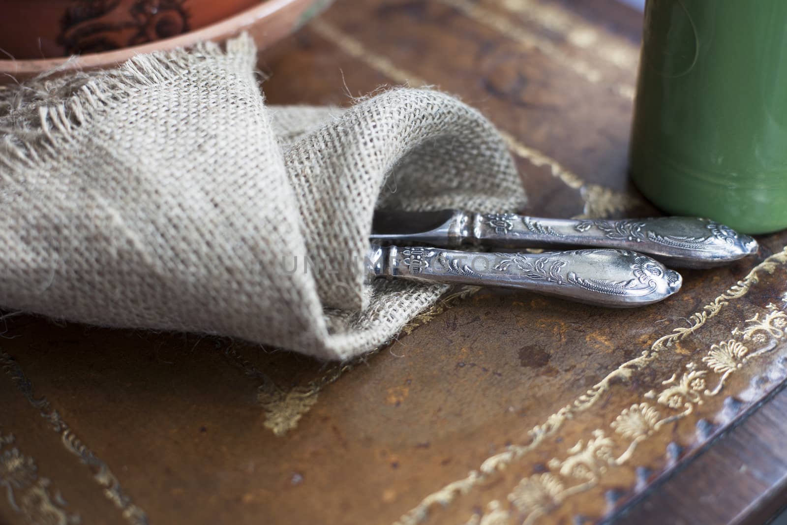 Cutlery wrapped in a burlap cloth on a vintage table.