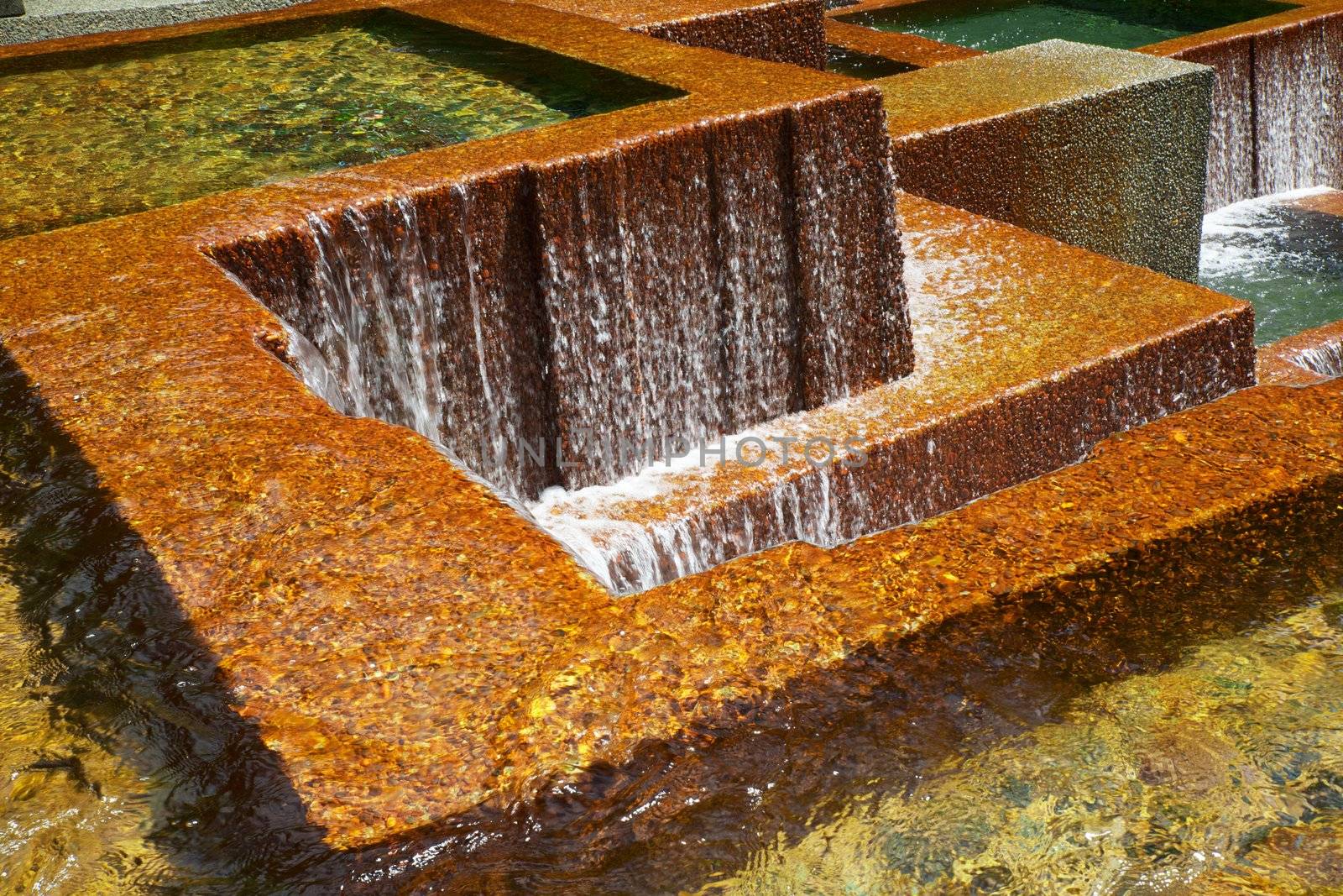 Multiple pools with water falls over golden concrete walls