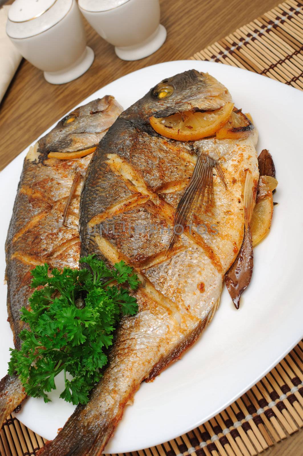 Dorado baked fish with lemon on a plate close-up