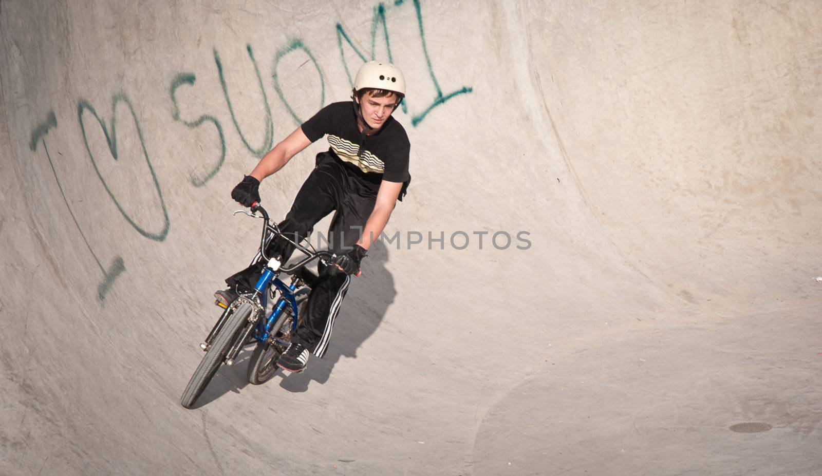 Teen boy rides a bicycle in the bike park .