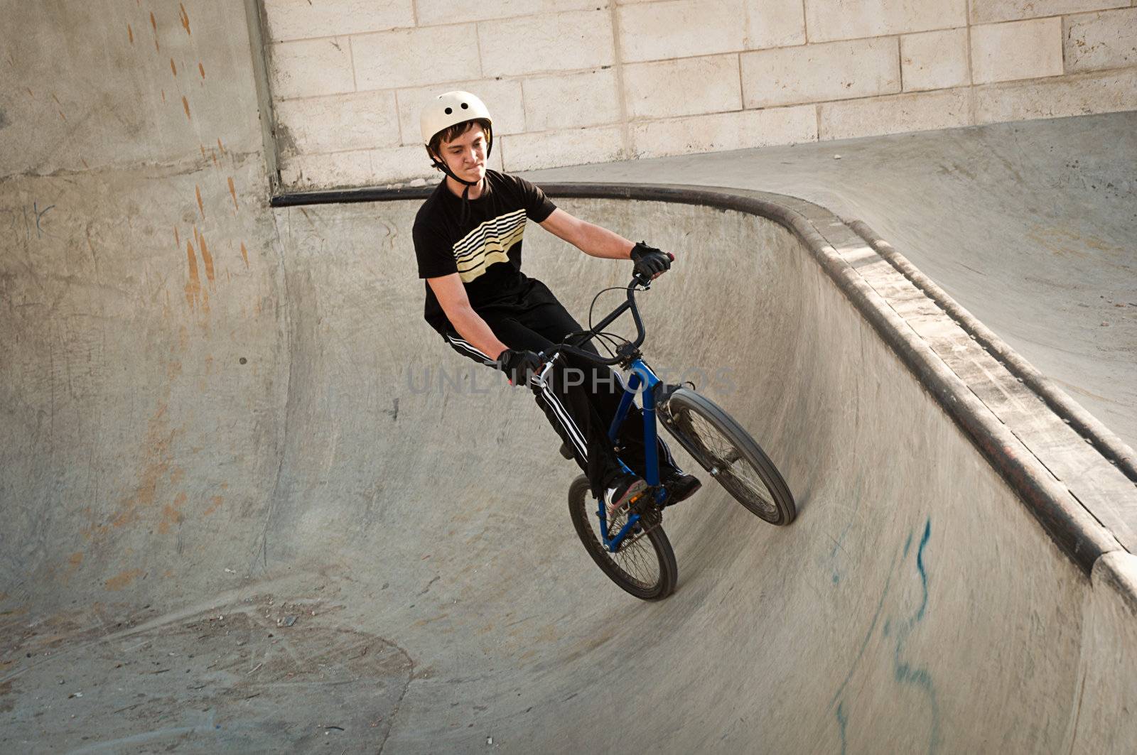 Teen boy rides a bicycle in the bike park .