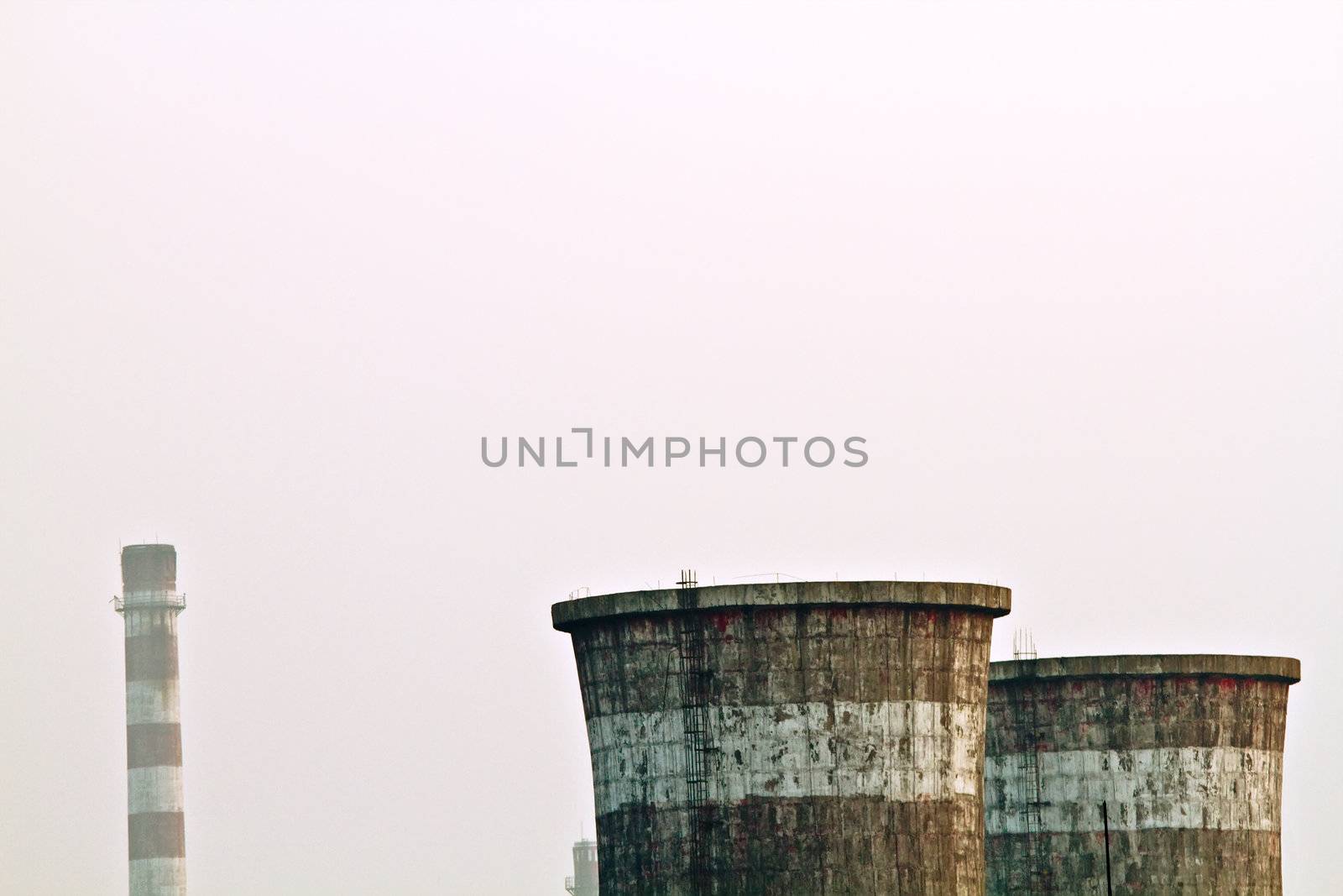 Closeup landscape photo of factory power plant chimenys in fog