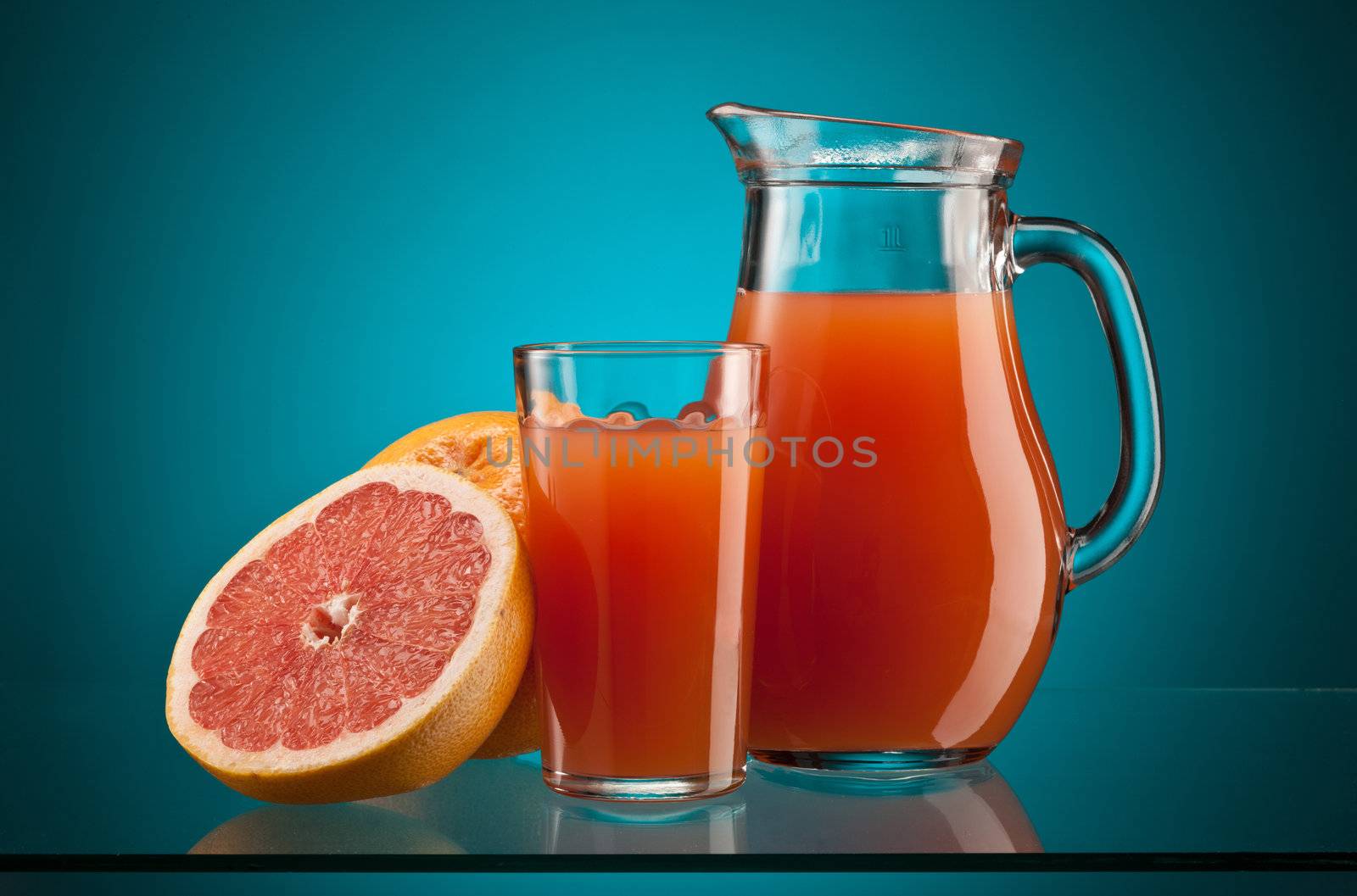 fresh grapefruit juice in the glass and jar over blue