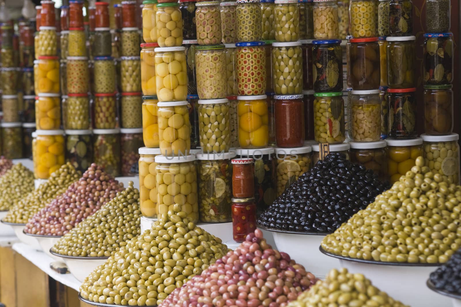Market stall selling fresh olives and bottled food in the main souk of Marrakesh, Morocco.