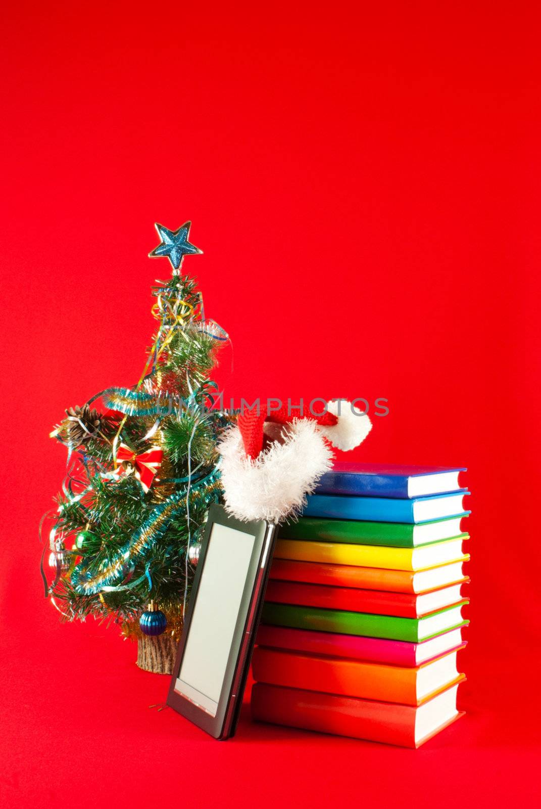 Electronic book reader with stack of books against red background