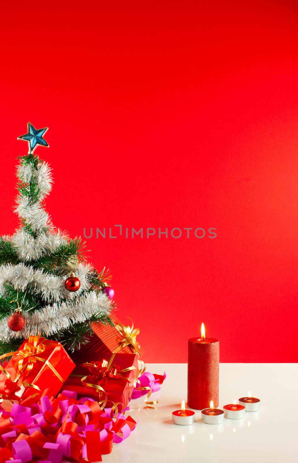 Christmas gifts with candles over red background