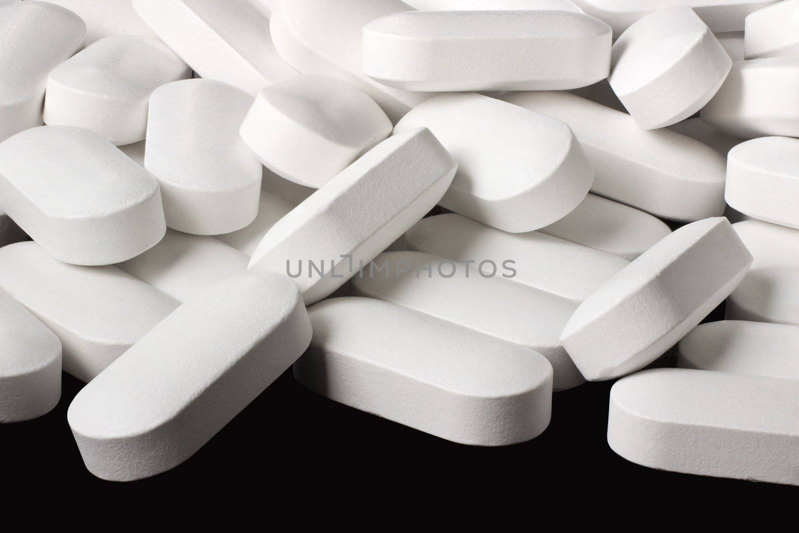 A pile of white tablets on a black background