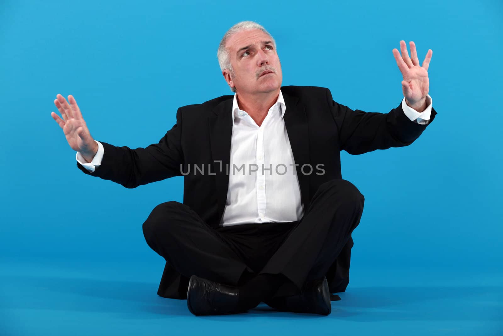 mature businessman gesturing on blue background