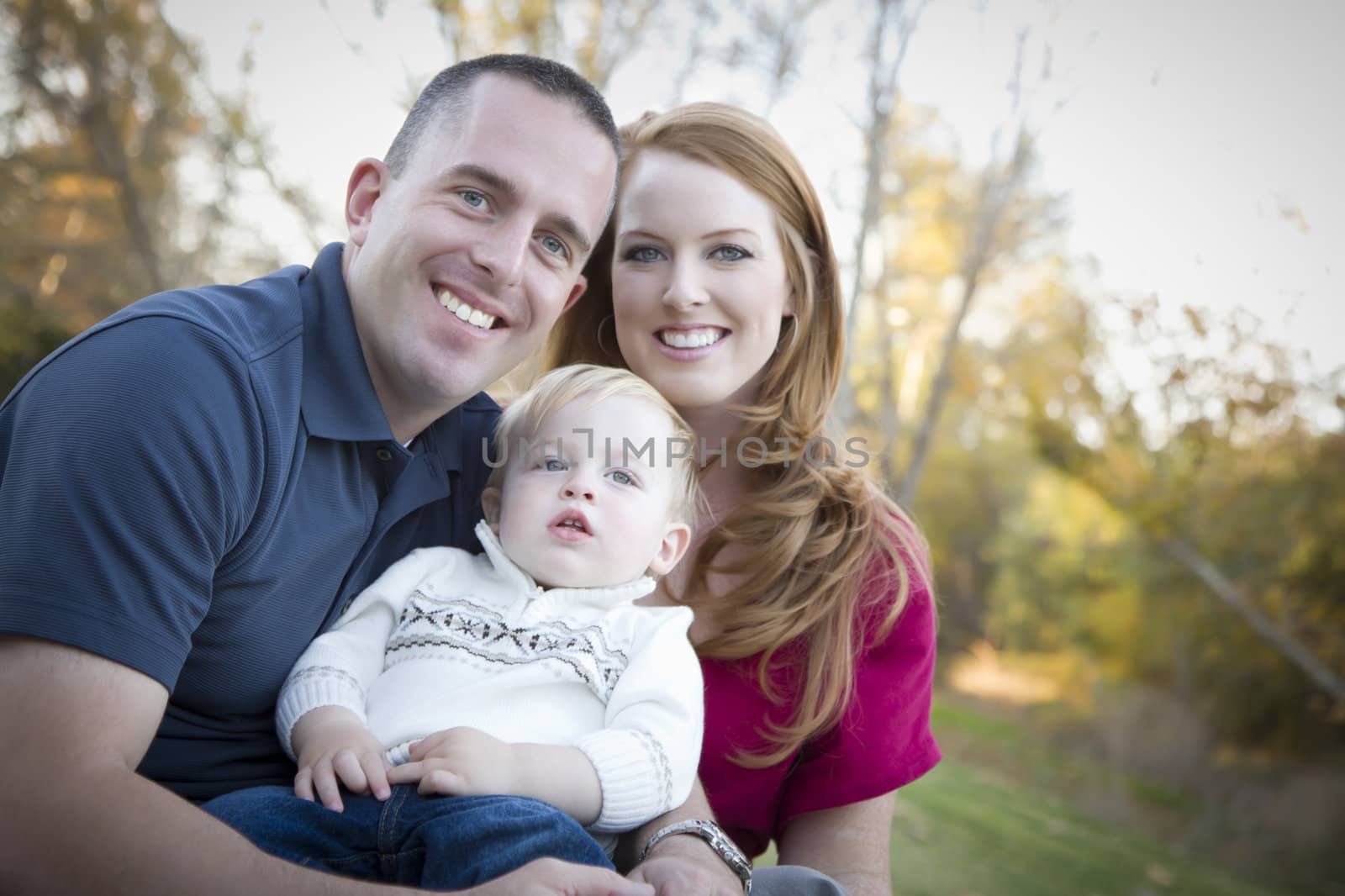 Young Attractive Parents and Child Portrait Outdoors at a Park.
