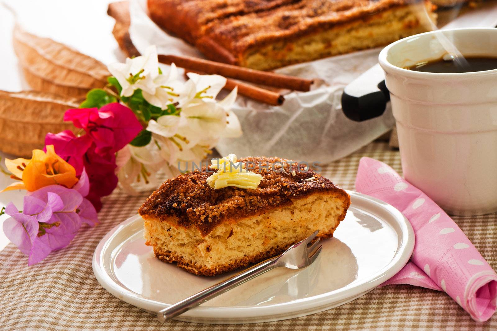 A sheet cake with cinnamon sugar butter and a hot cup of coffee