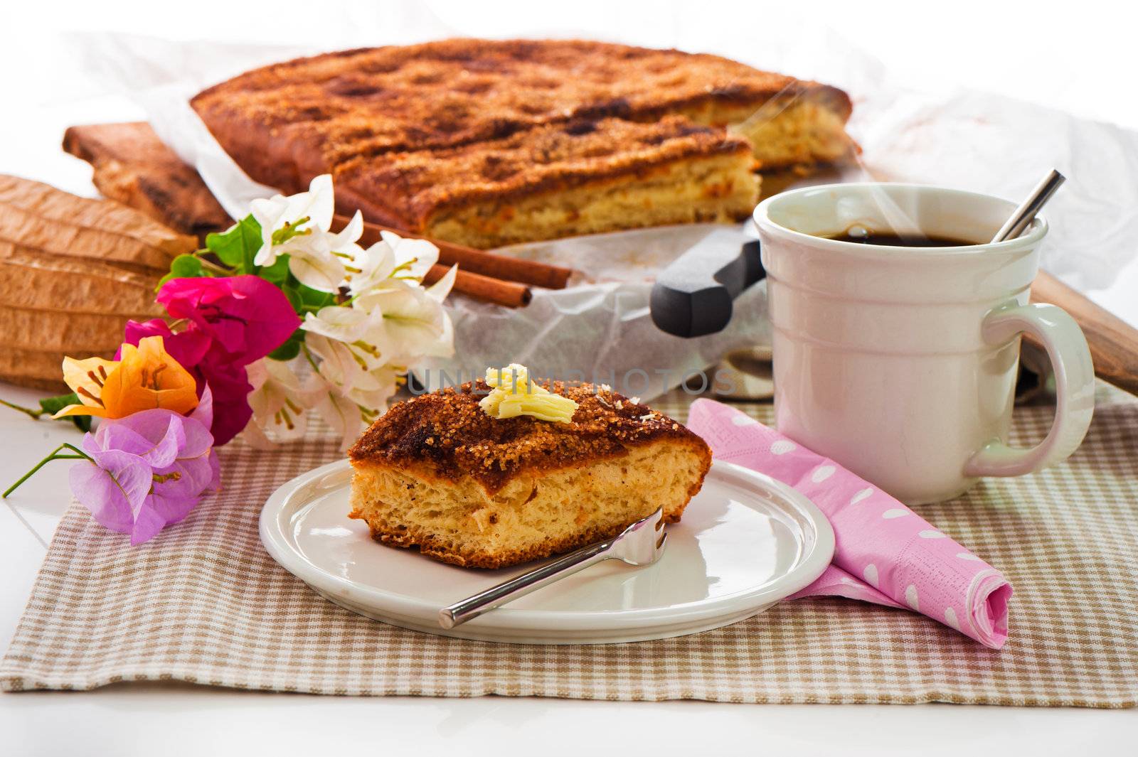 A sheet cake with cinnamon sugar butter and a hot cup of coffee