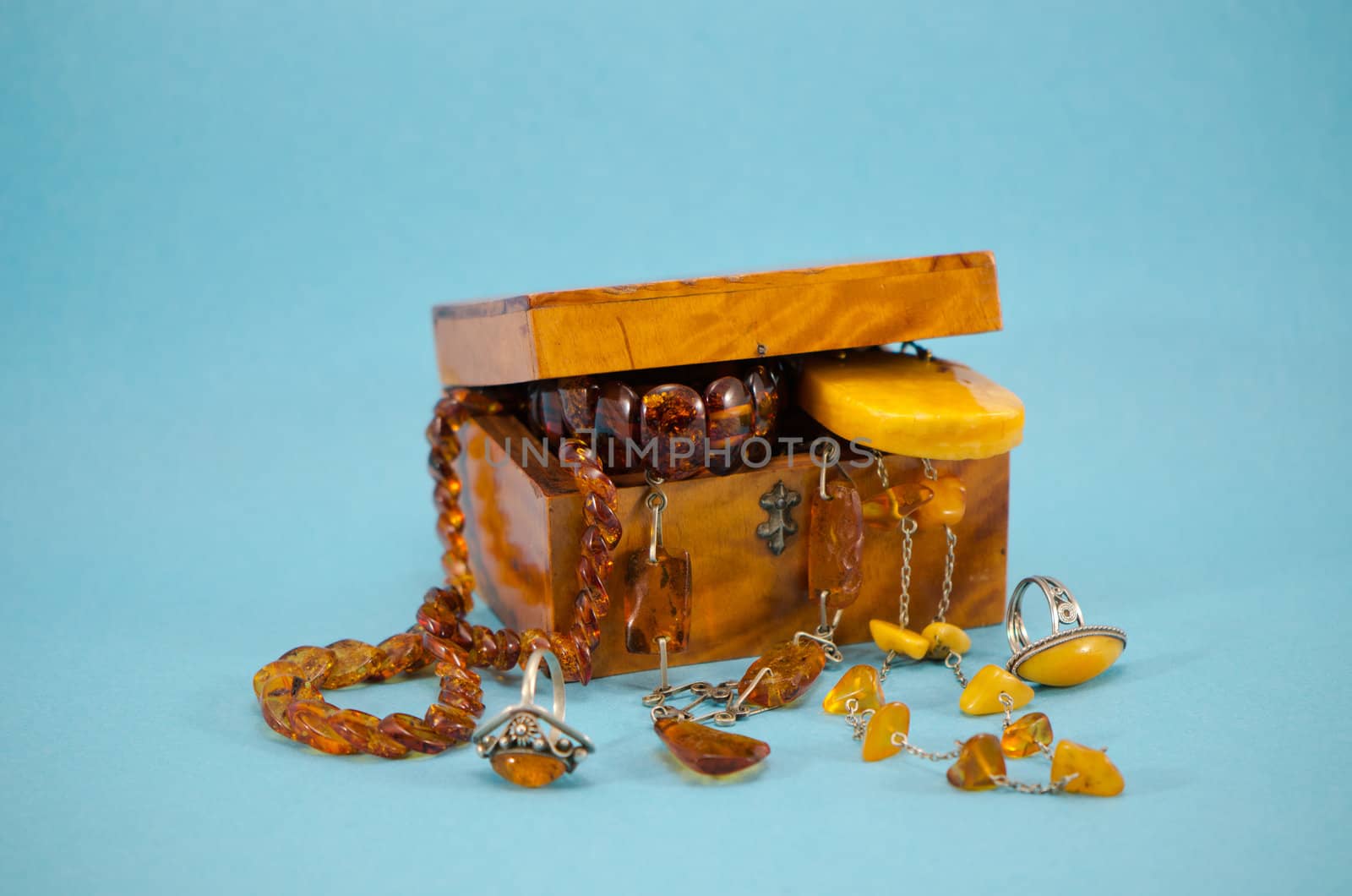 amber apparel jewelry ring bracelet in retro wooden box on blue background.