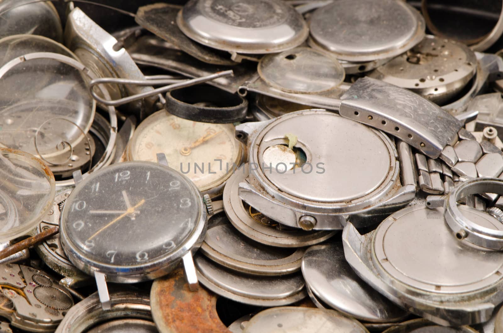 retro old watches clocks and parts pile heap closeup.
