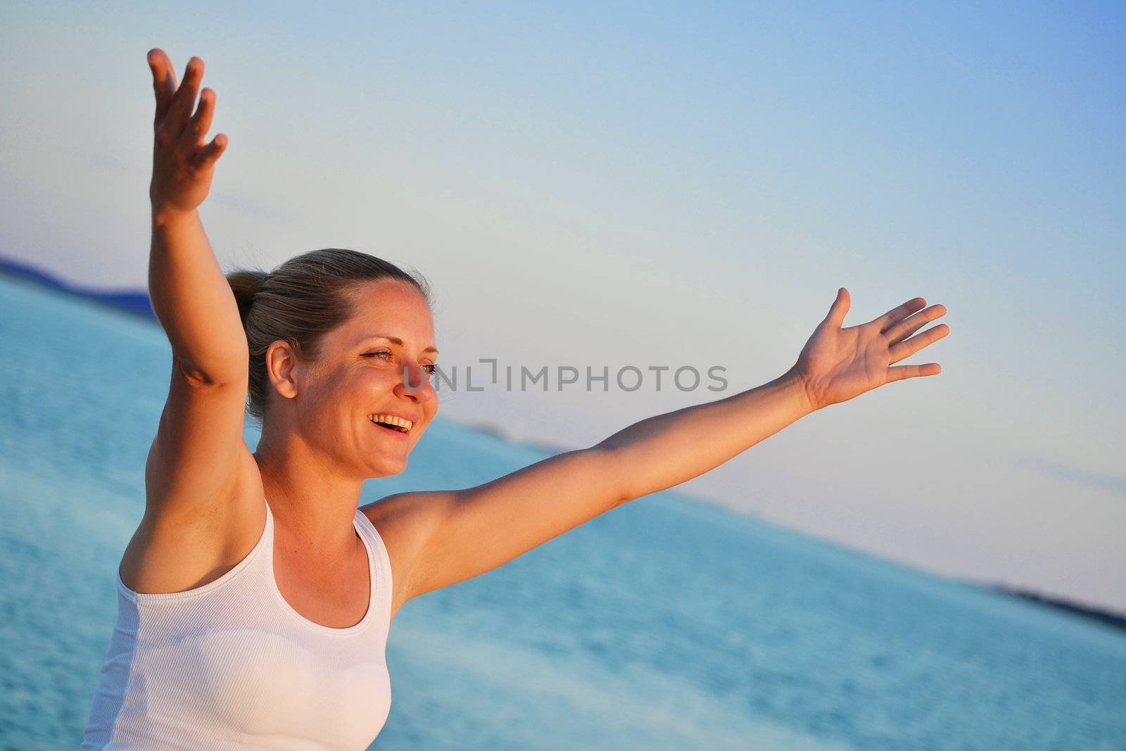 Young woman with hands up expressing joy on the beach 