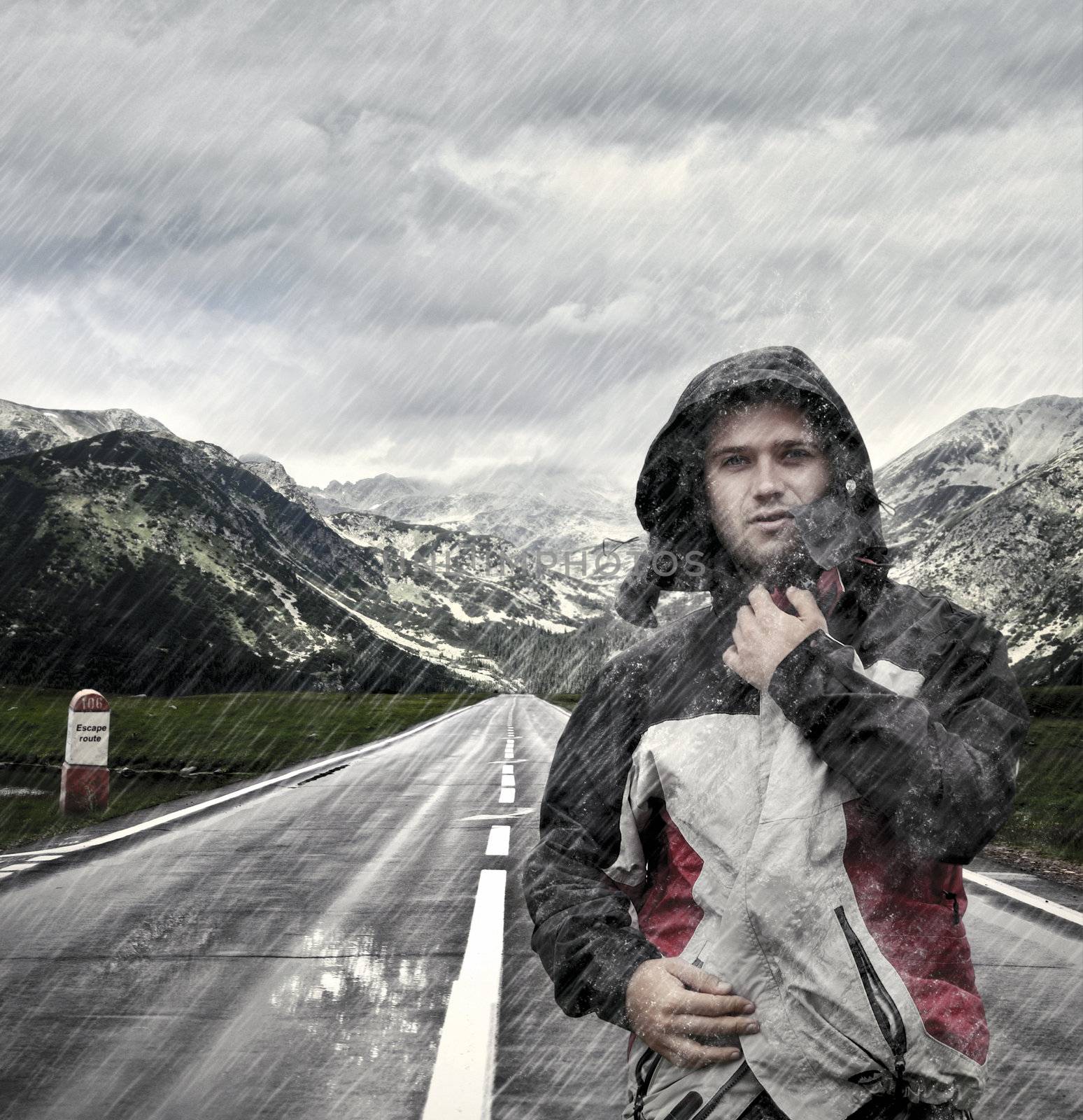 Young man walking on deserted street while is raining