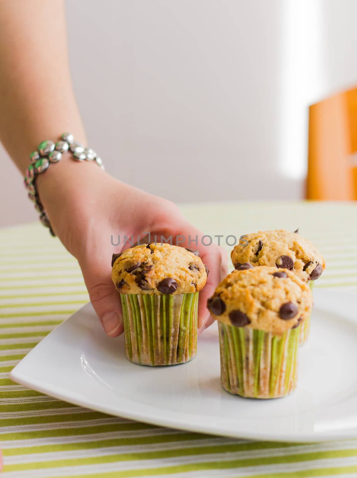 Nice girl hand taking chocolate chip muffin at breakfast by doble.d