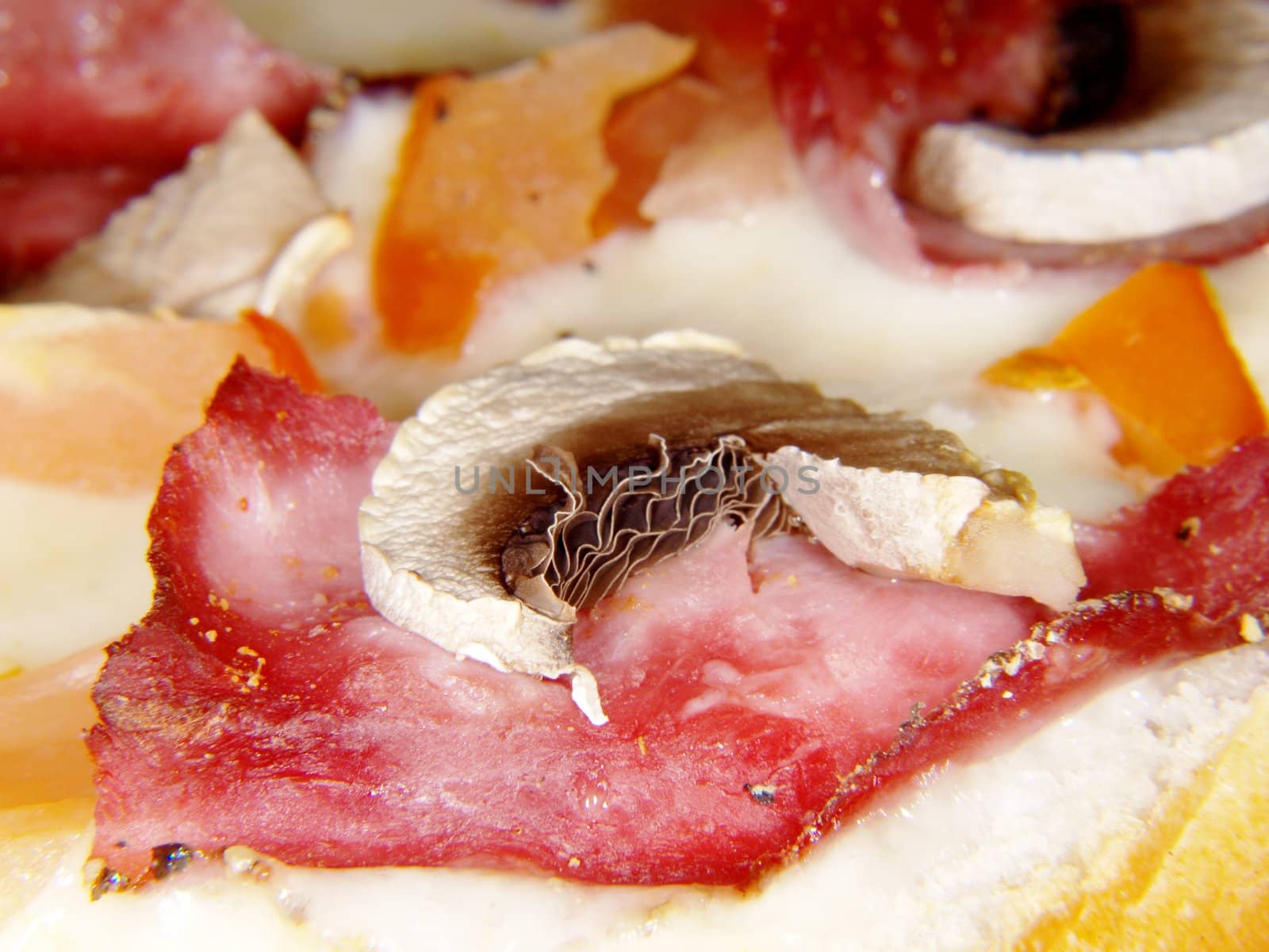 Sliced champignon on top of piece of ham and melted cheese