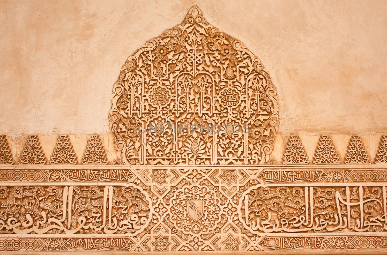 Arabic stone carvings on a wall in the Nasrid Palaces of the Alhambra of Granada, Spain.