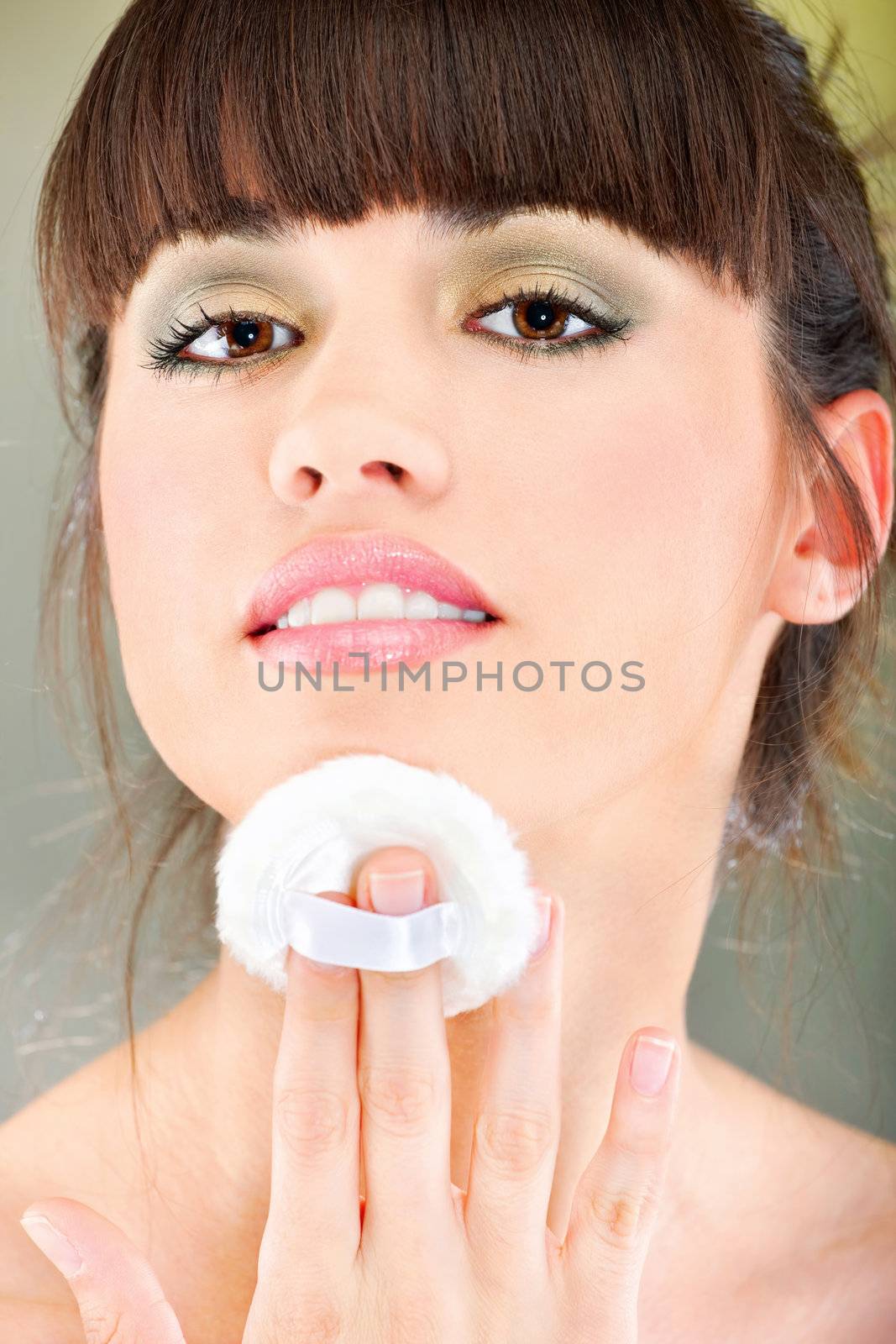 woman applying make up with cosmetic sponge by imarin