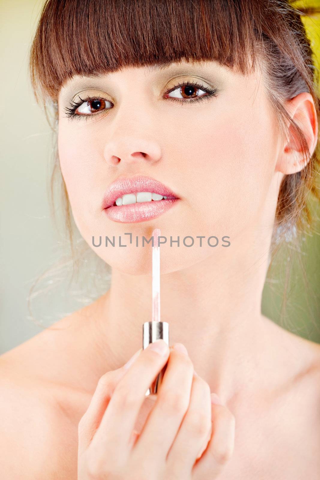 Pretty woman putting lipstick on her lips