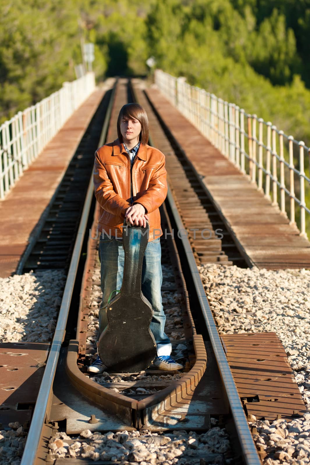 Musician with his guitar on top of a railway bridge