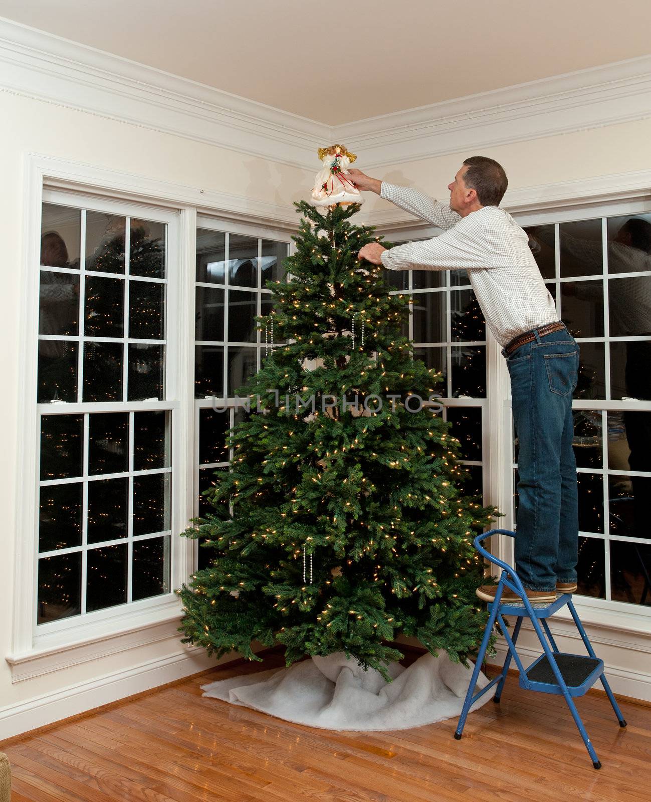 Senior man decorating a Christmas tree in family home