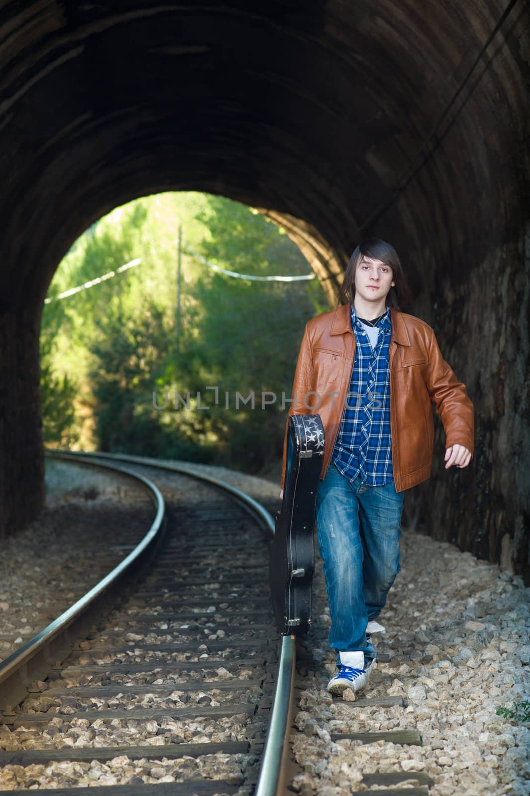 Cool guitarist portrayed inside a railway tunnel