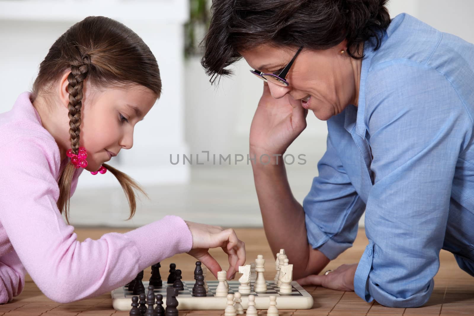 Mother and daughter playing chess by phovoir