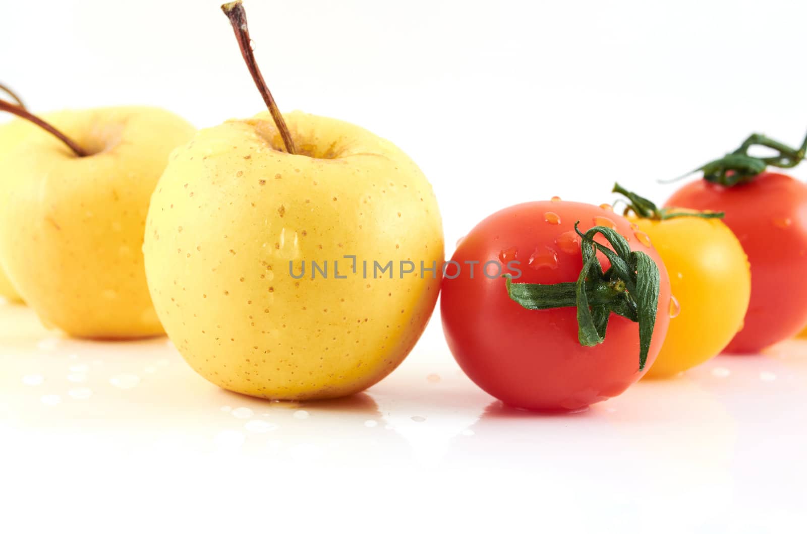 Juicy apples and tomatos  in drops of water on a white background