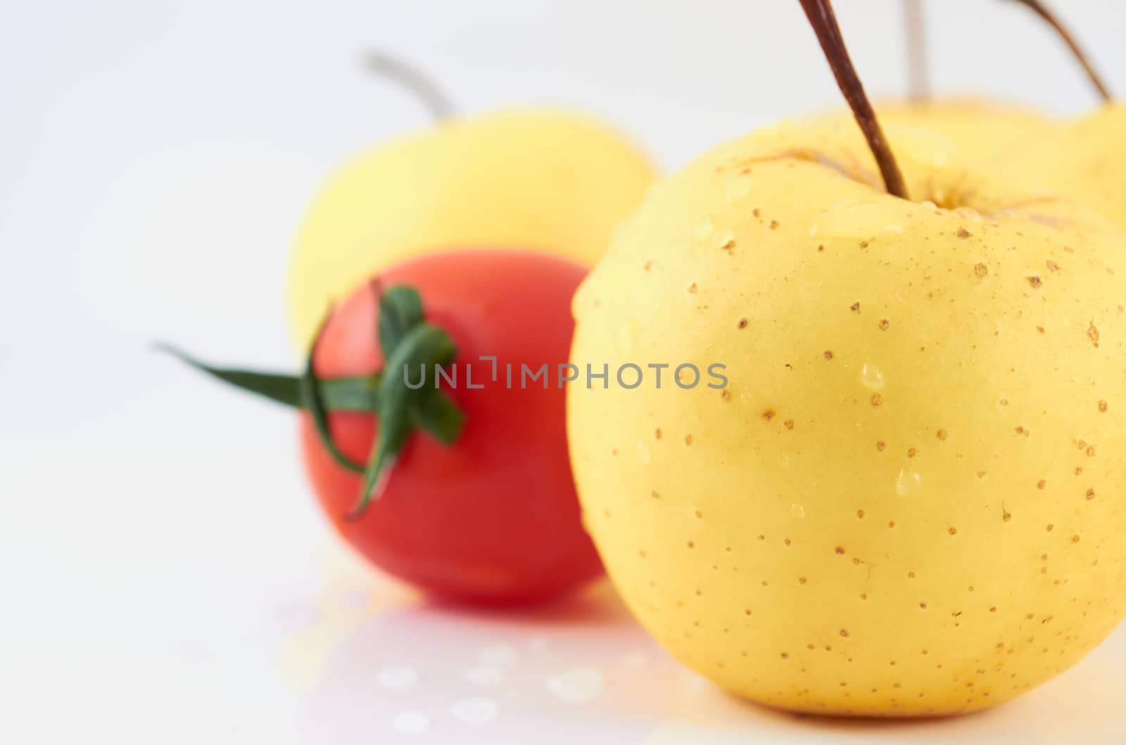 Juicy apples and tomato in drops of water on a white background