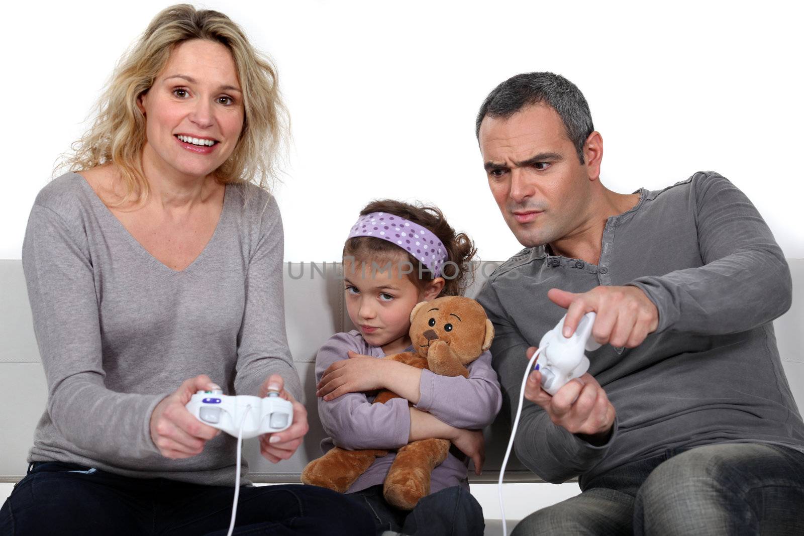 Man and woman playing to video games with little girl pouting Lacrouts_Isabelle_230311,Paniandy_Eric_230311,Armand_Lea_230311