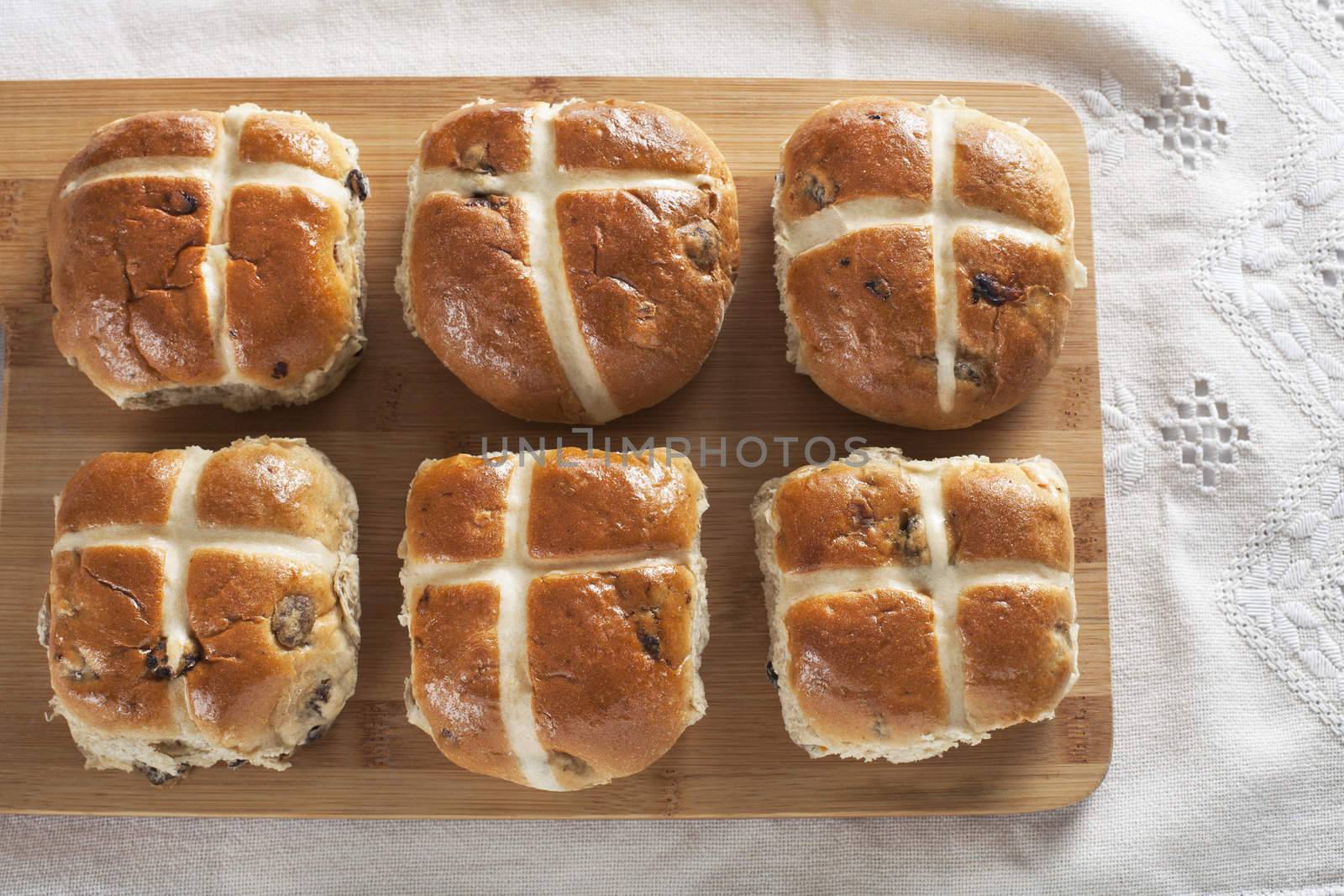 Six hot cross buns on a wooden cutting board