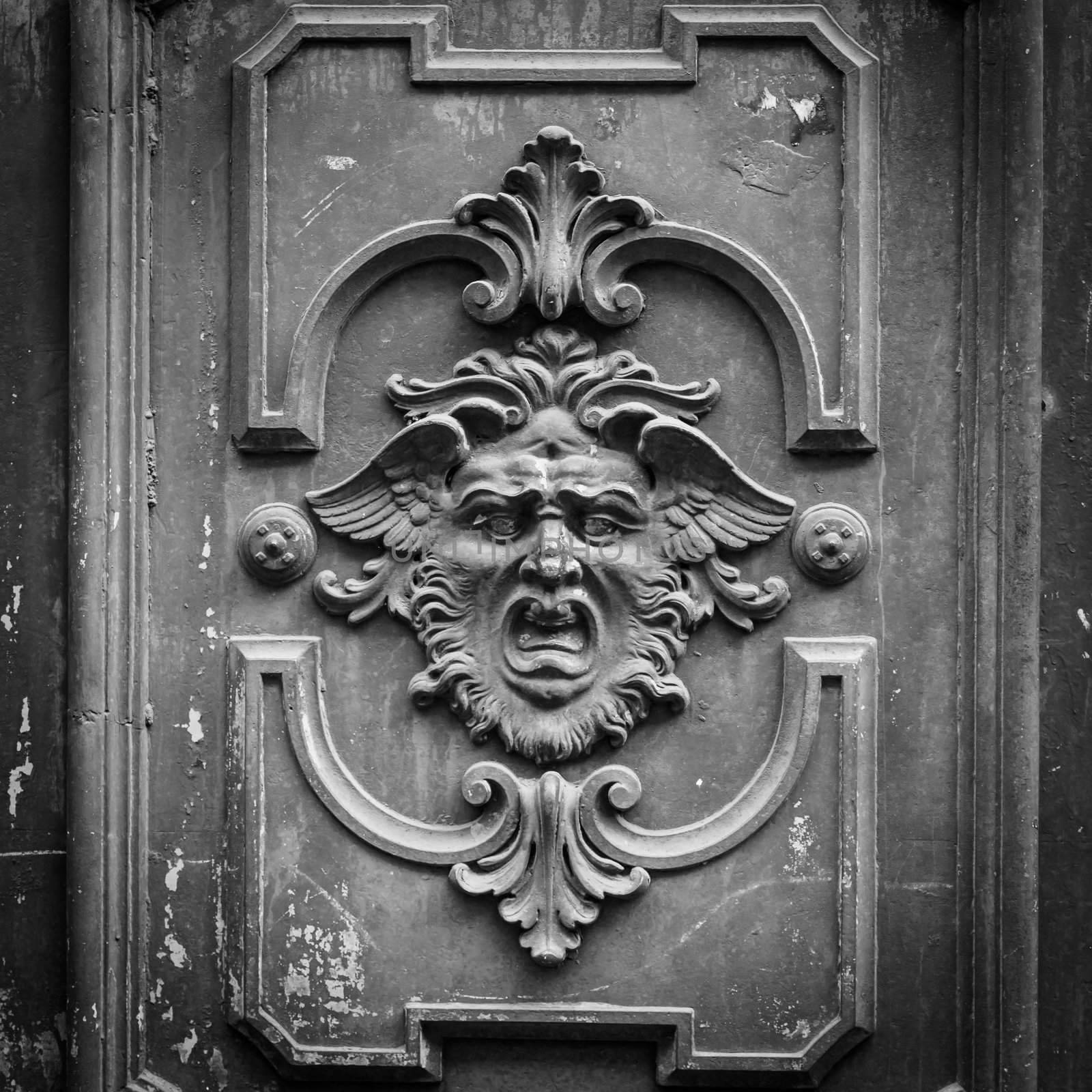 Gothic mask on an old wodden door in Milan - Italy