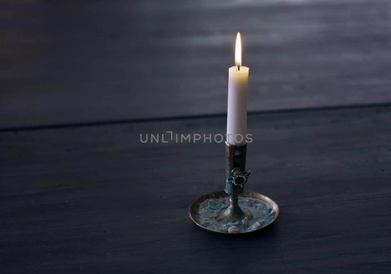 Lonely Candle on dark wooden table.