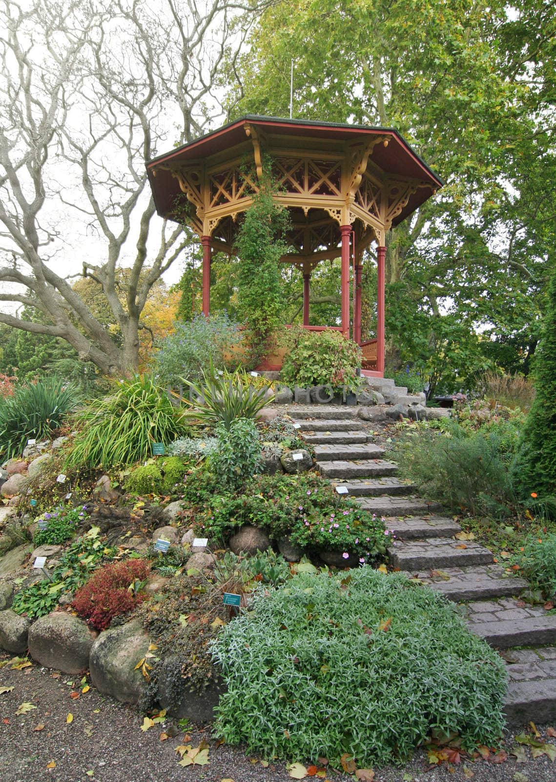 Chinese garden gazebo surrounded by plants and flowers.