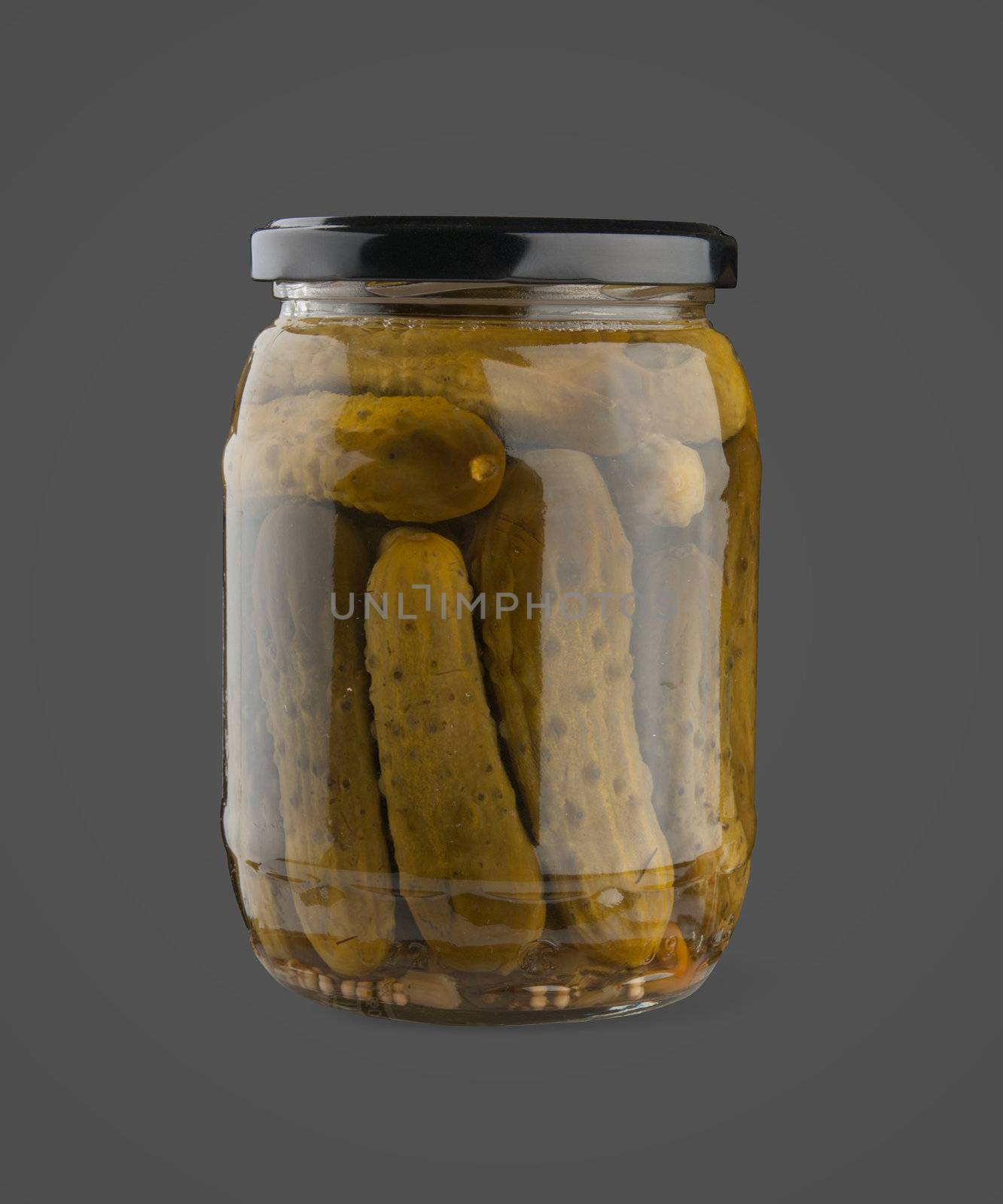 Marinated cucumbers in the glass jar on the dark grey