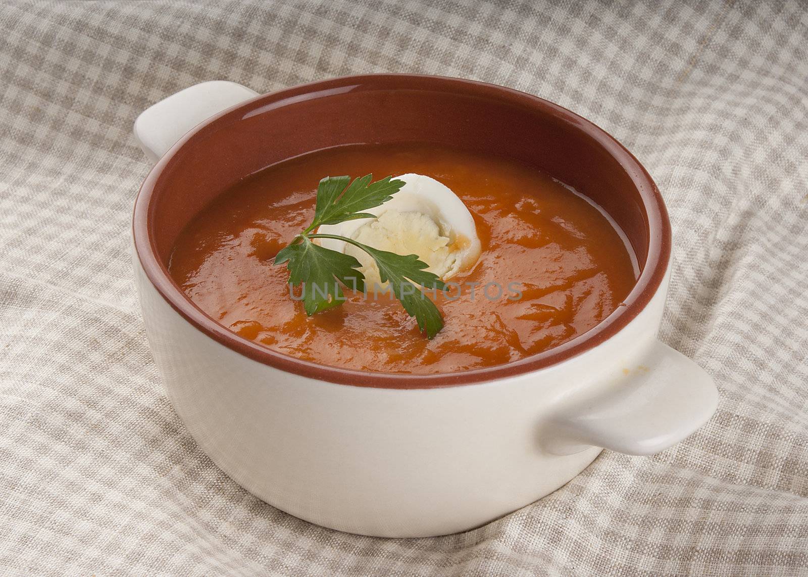 Tomato soup with parsley and boiled egg in the brown and white bowl
