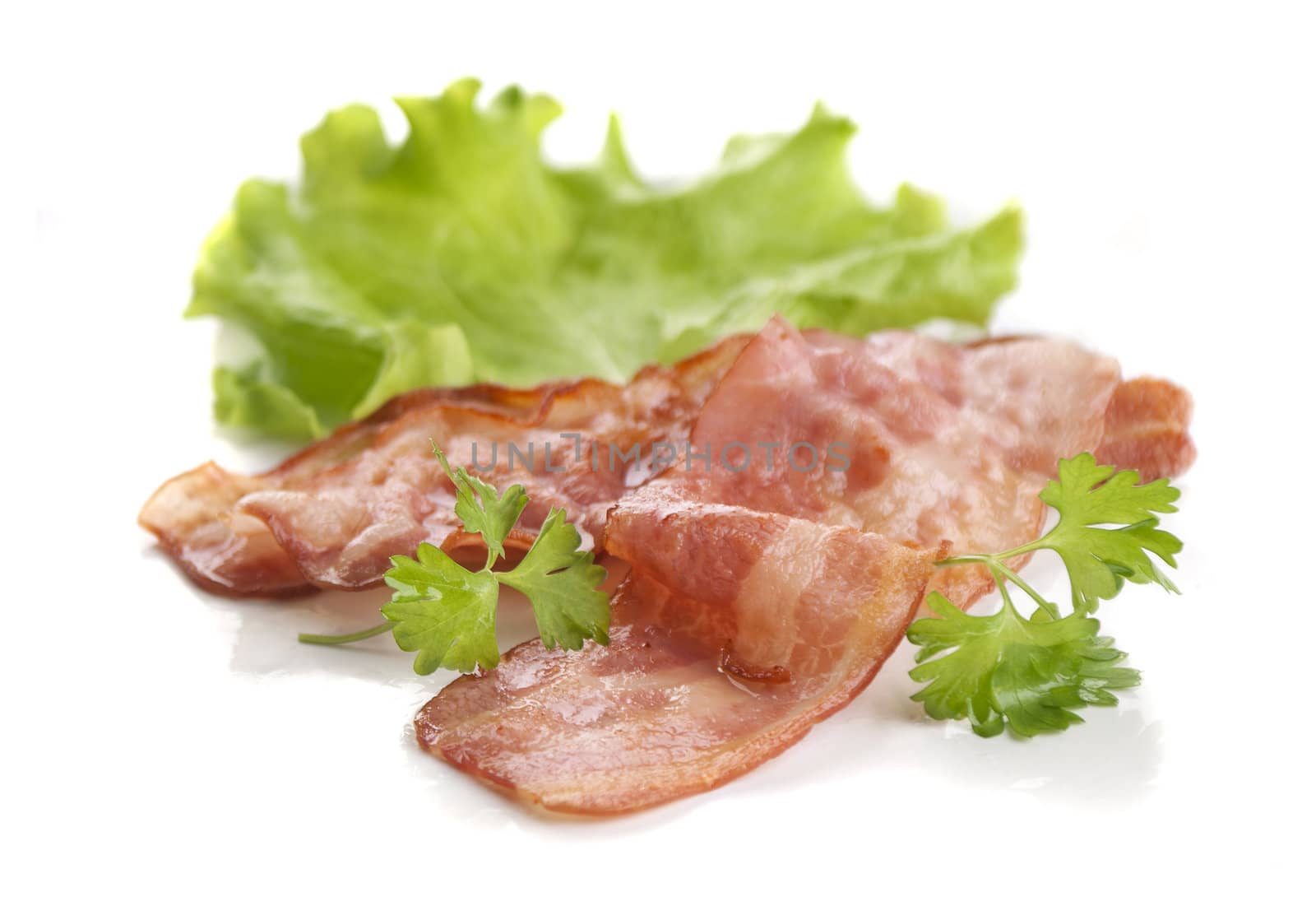 Two pieces of fried bacon with parsley and lettuce on the white