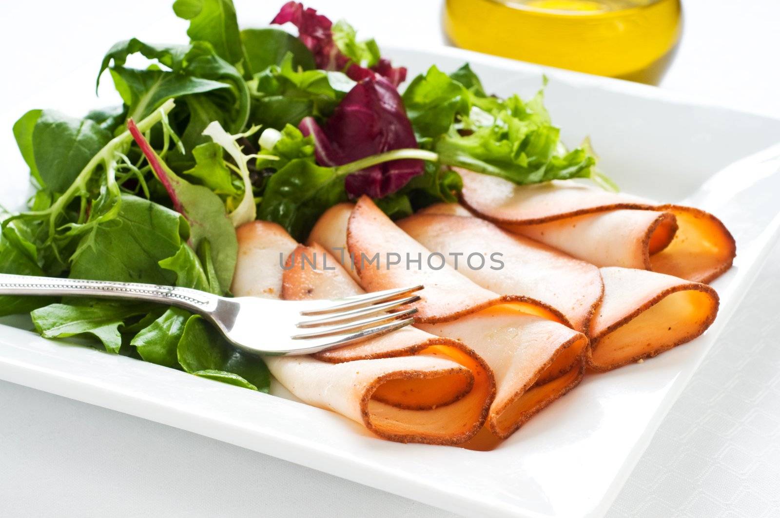 Plate of prepared meats served with fresh salad greens.