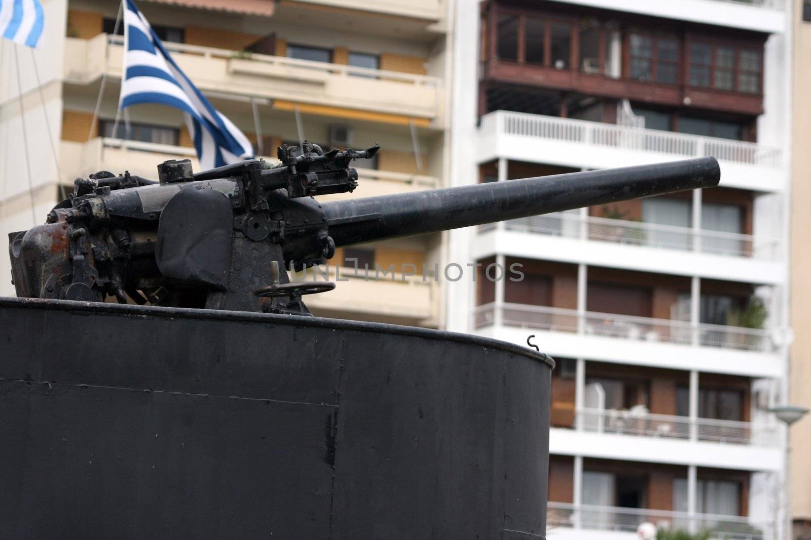 antique fire gun from old navy submarine with houses blur in background  at piraeus athens greece