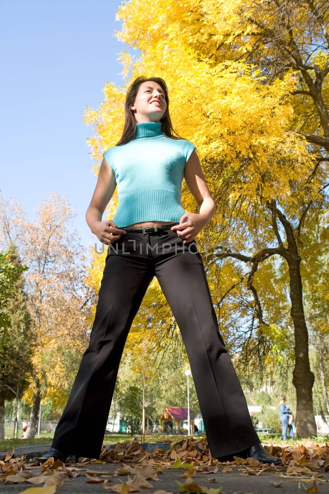 Autumn. The beautiful young woman against yellow leaves and blue sky.